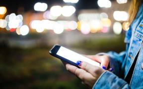 Woman holding a mobile phone with a bright glowing screen