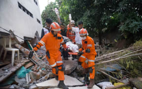 Rescue personnel evacuate earthquake survivor Ida, a food vendor, from the rubble of a collapsed restaurant in Palu, Indonesia's Central Sulawesi.