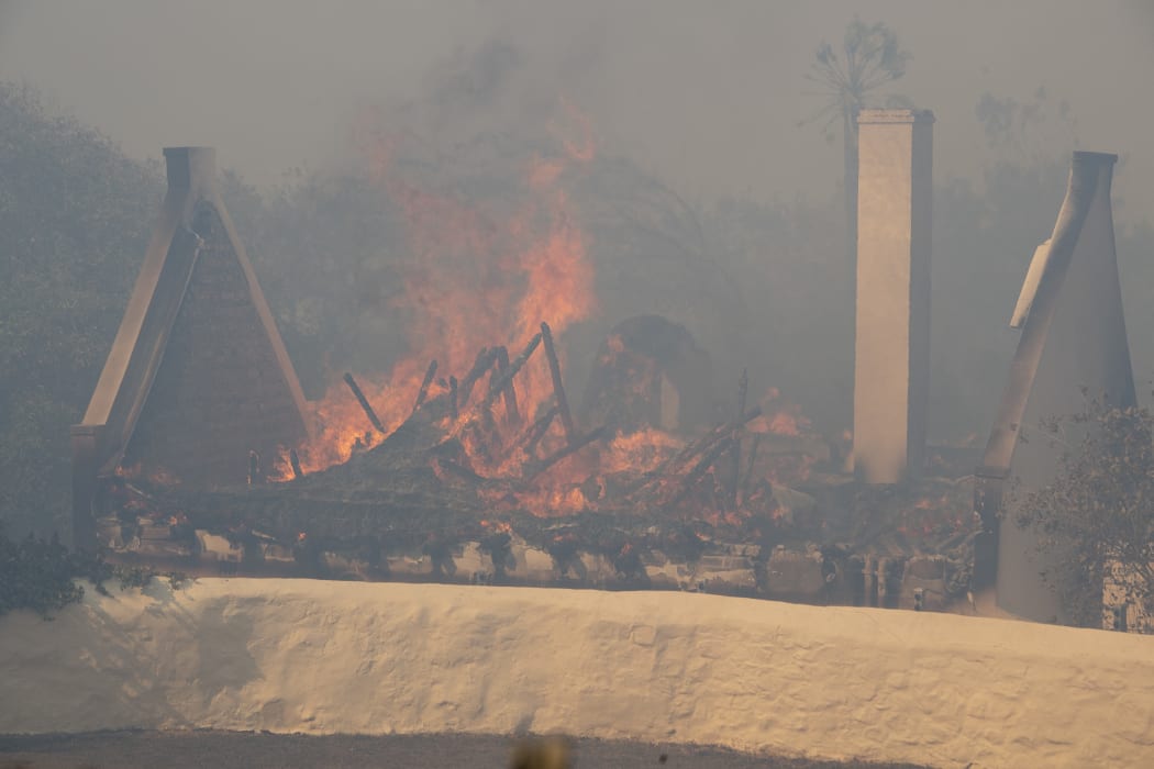 A historic Cape Dutch building burning as a forest fire rages on the foothills of Table Mountain, above the University of Cape Town.
