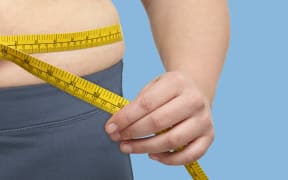 Overweight woman measuring her waist with a tape measure. (Photo by SCIENCE PHOTO LIBRARY / R3F / Science Photo Library via AFP)