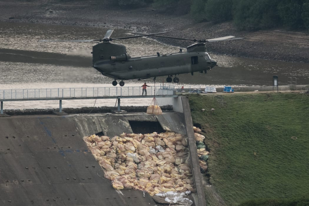 An RAF Chinook helicopter drops more bags of aggregate on the damaged section of spillway of the Toddbrook Reservoir dam above the town of Whaley Bridge in northern England on 4 August 2019.