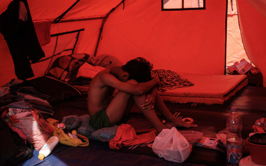 A young man rests in a makeshift shelter built for evacuees affected by a flash flood in Aceh Tamiang, Northern Sumatra, on December 13, 2025. Devastating floods and landslides have killed 1,006 people in Indonesia, rescuers said December 13 as the Southeast Asian nation grapples with the huge scale of relief efforts. (Photo by Yasuyoshi CHIBA / AFP)