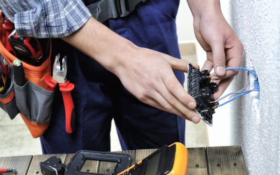 Young electrician at work on switches and sockets of a residential electrical installation.