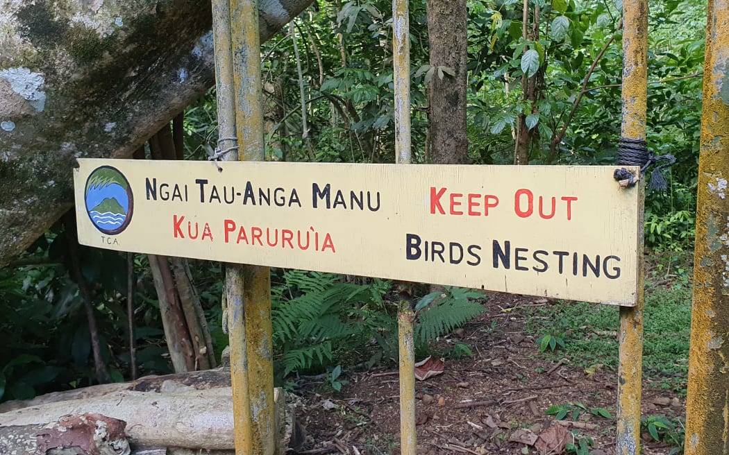 The entrance to the conservation area with poles holding up a sign that says 'Ngai Tau-Anga Manu - Kua Paruruia' 'Keep Out - Birds Nesting'