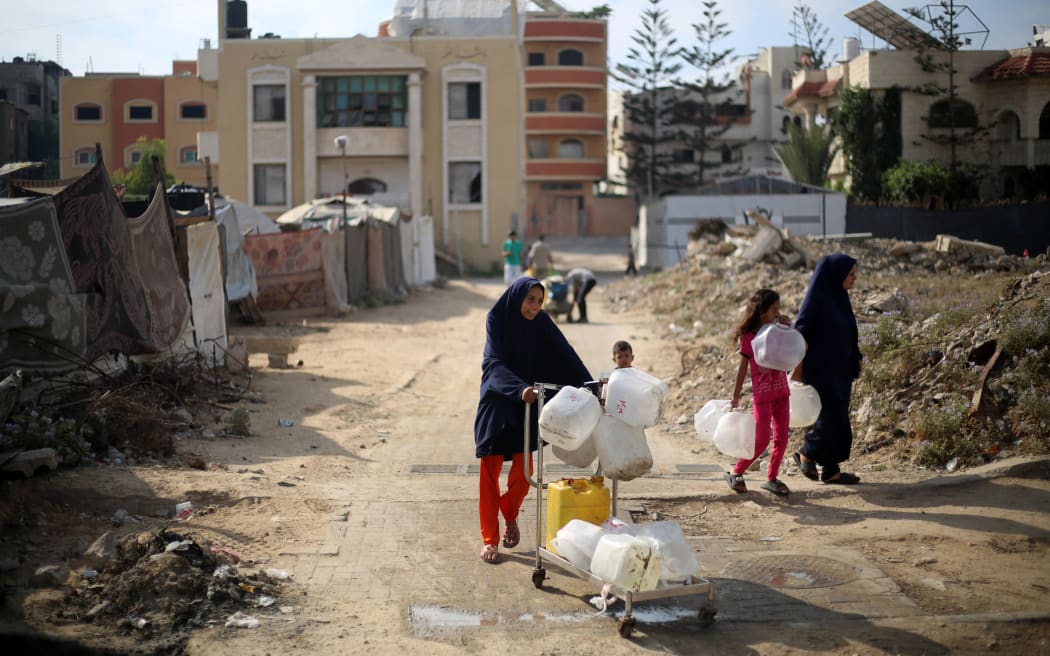 Displaced Palestinians carry empty containers on their way to fetch water at a distribution point in the Nuseirat refugee camp in the central Gaza Strip on 10 July 2025.