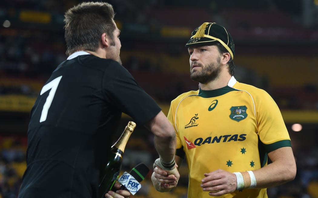 The All Blacks captain Richie McCaw presents the Wallabies Adam Ashley Cooper with a bottle of champagne for his 100th cap.