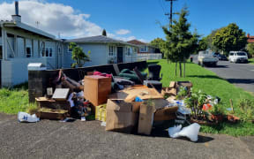 Flood-damaged furniture and  household items are piled on the roadside on a Mt Roskill street.