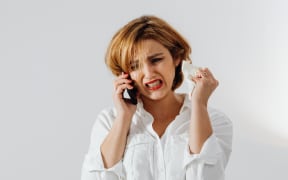 Upset woman on her phone wearing a white shirt