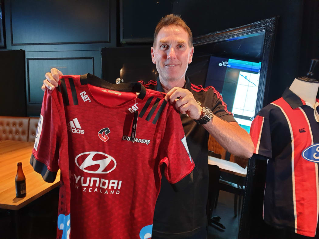 Crusaders fan Anthony Mercer hold a jersey with the team's new logo.