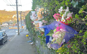 Flower bouquets have been left outside a house on Dundas Street, Dunedin, where a university student died after being fatally hurt at an overcrowded part.