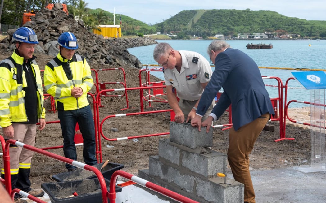 chief military putting the first stone of the docking quay.