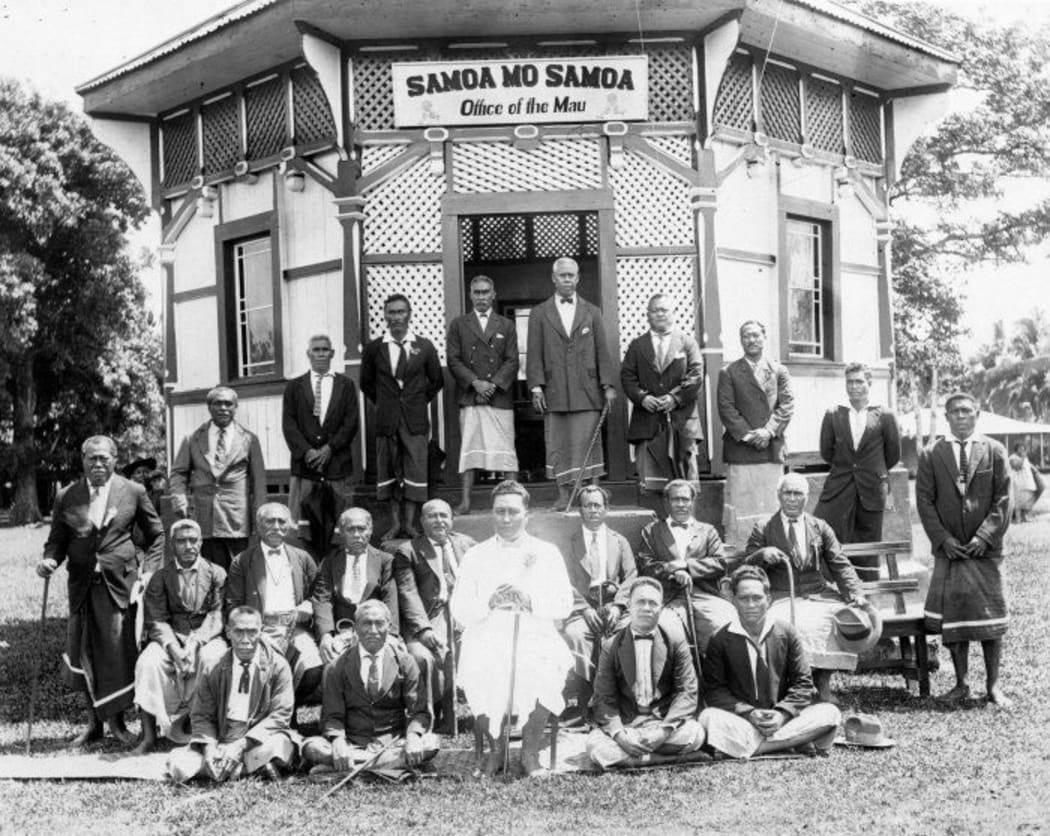 Shows group of men, including Tupua Tamasese Lealofi III (dressed in white), gathered around the office of the Mau ca 1928 with the slogan Samoa Mo Samoa over the door.