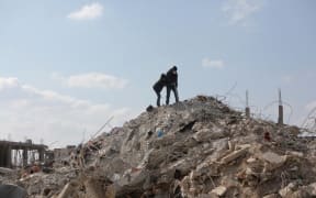 A Syrian man and boy inspect the rubble of a building in the town of Jindayris, in the rebel-held part of Syria's Aleppo province on February 11, 2023, days after a deadly earthquake hit Turkey and Syria. (Photo by Bakr ALKASEM / AFP)