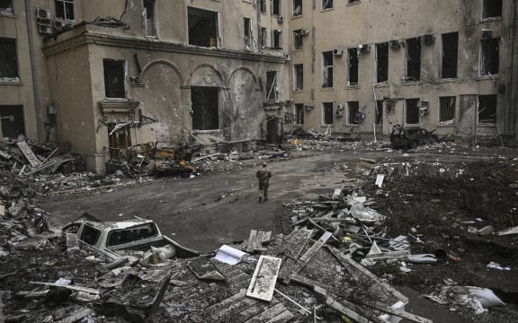 A Ukranian serviceman walks toward the destroyed regional headquarters of Kharkiv, 27 March, 2022.