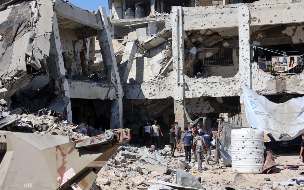 Palestinians check the damage in the al-Zahra school used as a refuge by displaced Palestinians after it was hit by an Israeli strike, in the Shujaiya neighbourhood of Gaza City on 8 August 2024, amid the ongoing conflict between Israel and the militant group Hamas. (Photo by Omar AL-QATTAA / AFP)