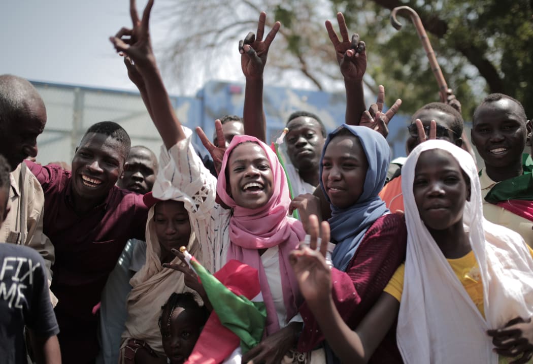 Sudanese men and women celebrate outside the Friendship Hall in the capital Khartoum where generals and protest leaders signed a historic transitional constitution