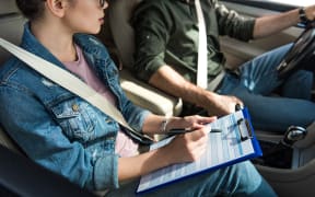 cropped image of student and teacher in car at driving test