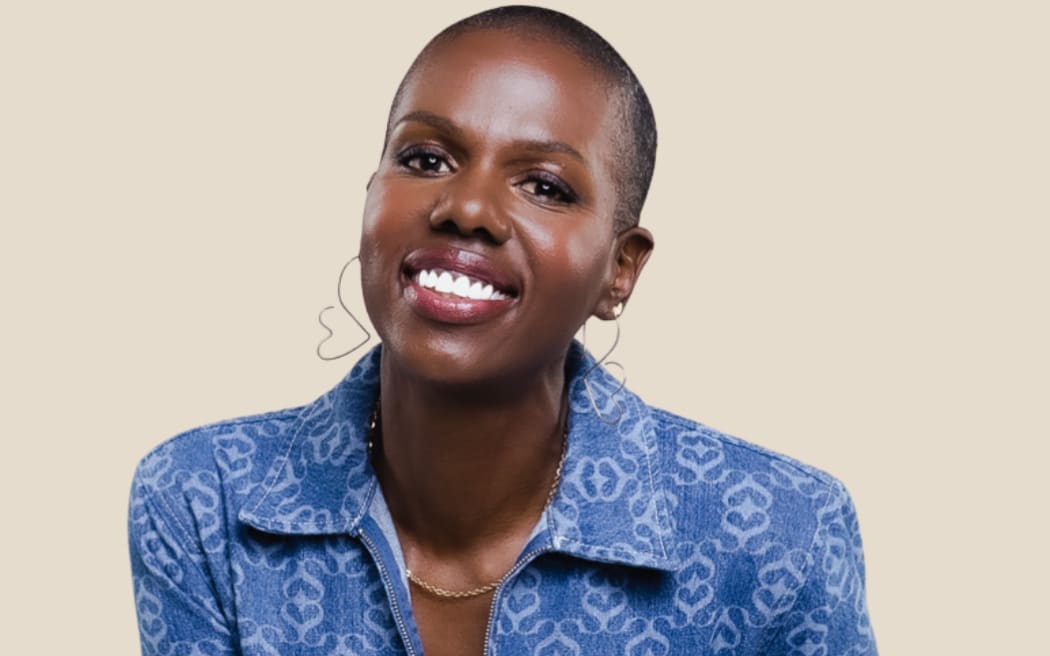 Francesca Hogi wearing a blue jumpsuit, smiles at the camera.