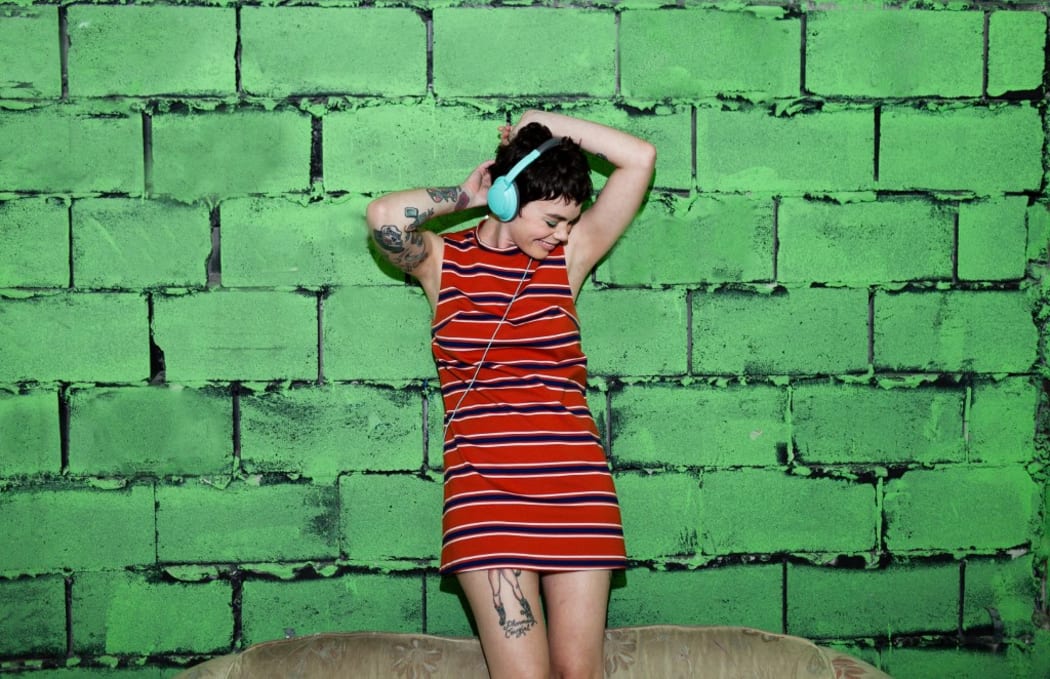 Mid adult woman with tattoos, wearing headphones, dancing (Photo by Zave Smith / Image Source / Image Source via AFP)