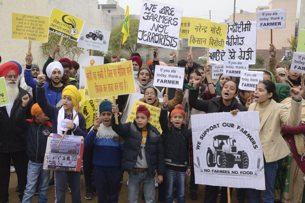 Students along with their parents hold placards and shout slogans in support of farmers protesting against the central government's recent agricultural reforms, in Amritsar.