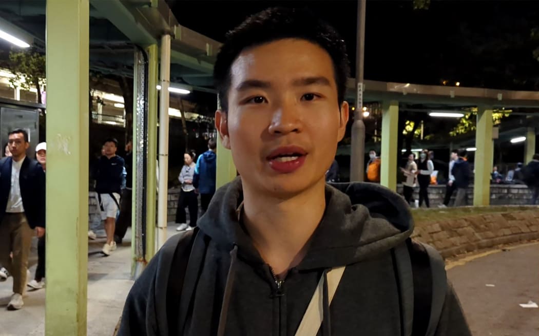 Miles Kwan, a 24-year-old student, speaks to AFP while handing out flyers outside a train station in Hong Kong's Tai Po district on November 28, 2025, following the deadly fire at the Wang Fuk Court residential complex. Local media reported that Kwan was arrested by national security police for sedition on November 29 after starting an online petition with 