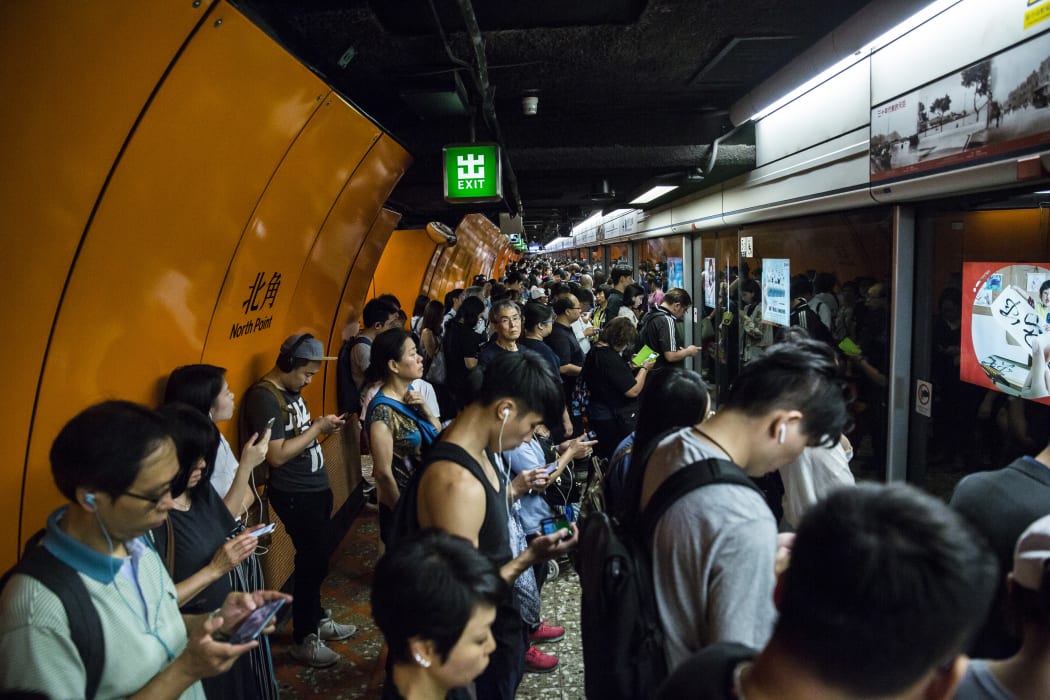 Commuters line up on a Mass Transit Railway (MTR) platform in Hong Kong on 30 July, 2019, after MTR services were resumed after being suspended by protesters demonstrating against a controversial extradition bill.