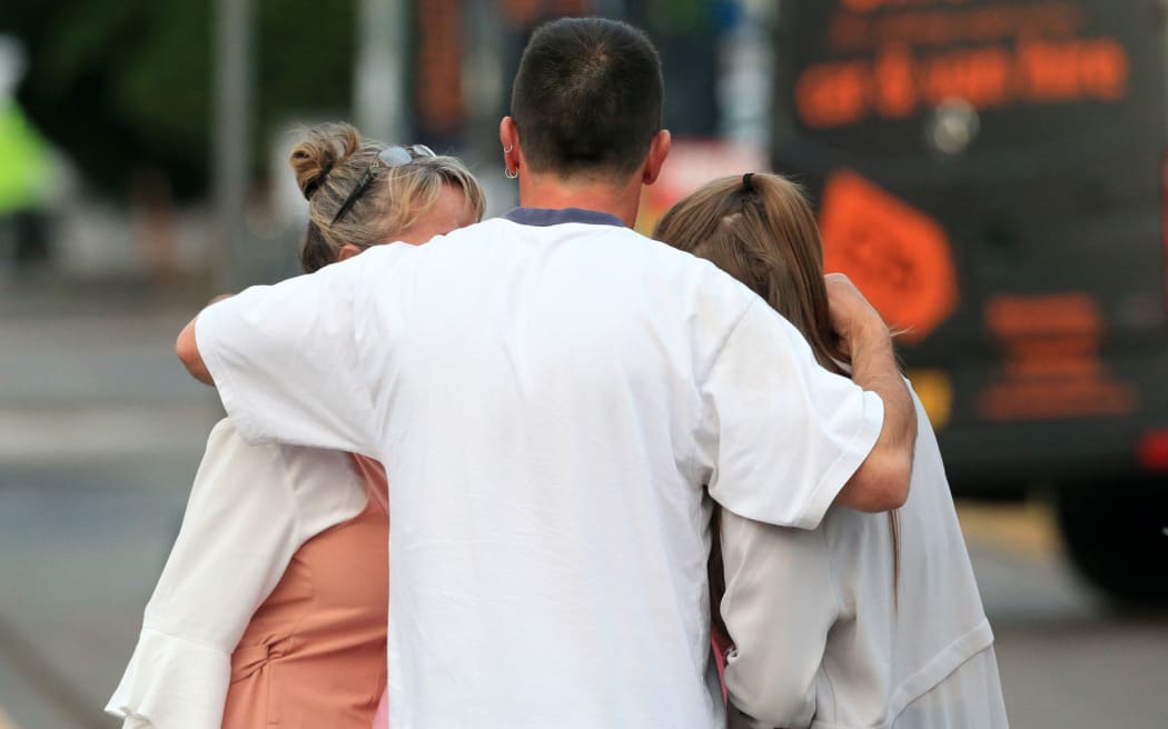 A man hugs his wife and daughter outside Manchester Arena.