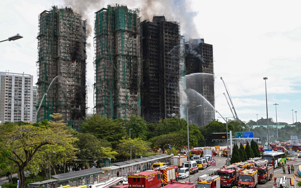 Firefighters spray water on flames as a major fire burns through several apartment blocks at the Wang Fuk Court residential estate in Hong Kong's Tai Po district on 27 November, 2025.