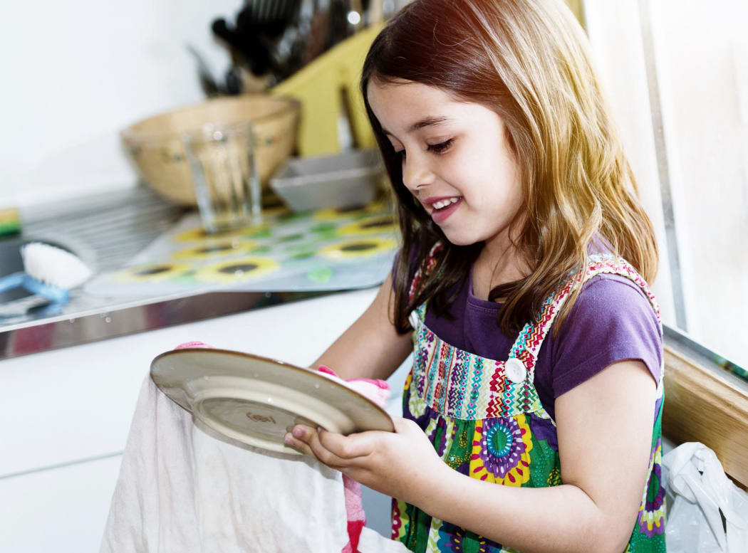 A photo of a very cute girl wiping the dishes in the kitchen