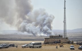 Smoke rises as Islamic State fighters and Kurdish armed groups clash in the Syria-Turkey border town of Kobane on 26 June.