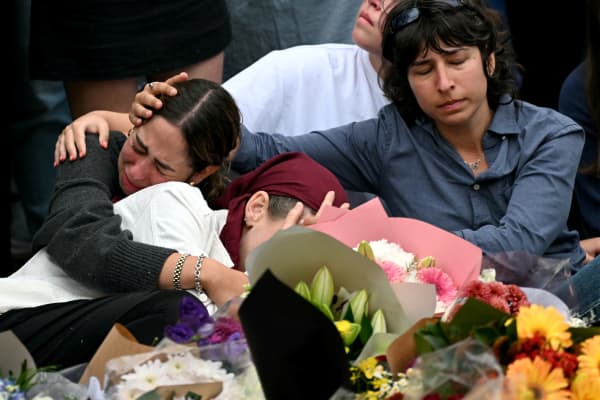 Family members of victims react as they stand with other mourners near tributes at the Bondi Pavilion in memory of the victims of a shooting at Bondi Beach, in Sydney on 16 December, 2025.