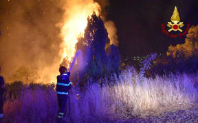 An image taken by Italian Firefighters "Vigili del Fuoco" shows a firefighter combating the fire raging around Palermo, Sicily, that has forced people from their homes, 10  August, 2021.