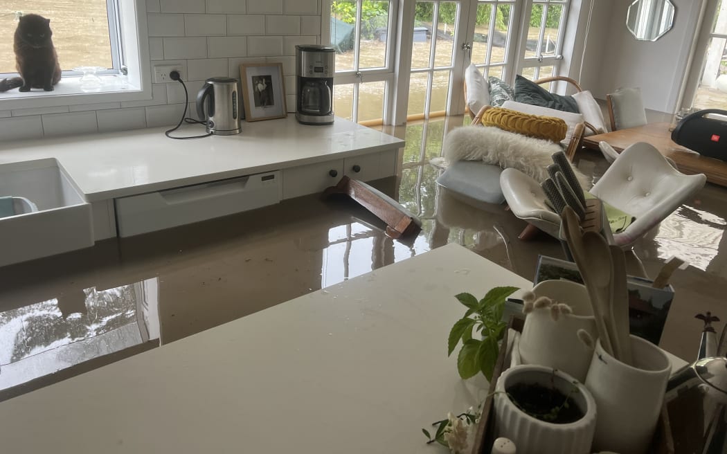 Dirty brown water has flooded the home of Derek Judge and his partner. It is almost at the height of the kitchen bench and dining table. Chairs are floating inside the house. Inside, the water is calm and still - but outside you can see that is moving swiftly.