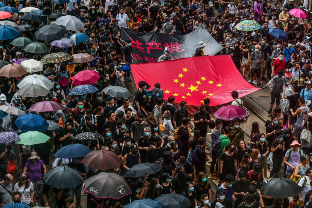 Protesters march with a banner that uses the stars of the Chinese national flag to depict a Nazi Swastika symbol in the Central district of Hong Kong.