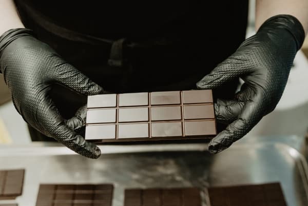 A bar of Solomons Gold Chocolate held by someone in black gloves