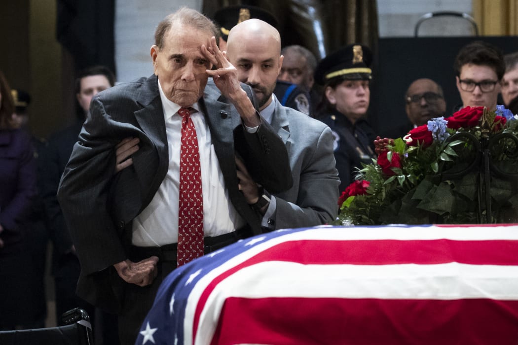 Former US Senator Bob Dole stands up and salutes the casket of the late former President George H.W. Bush as he lies in state at the U.S. Capitol, December 4, 2018 in Washington, DC