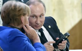 Russian President Vladimir Putin speaks with German Chancellor Angela Merkel during the first day of the COP21 climate change meeting in Paris.