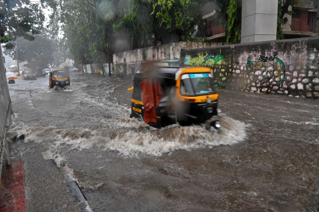 Auto rickshaws wade through a flooded street during heavy rains caused by the Cyclone Tauktae in Mumbai on May 17, 2021 (Photo by INDRANIL MUKHERJEE / AFP)