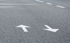 Arrow signs on asphalt road showing direction of movement