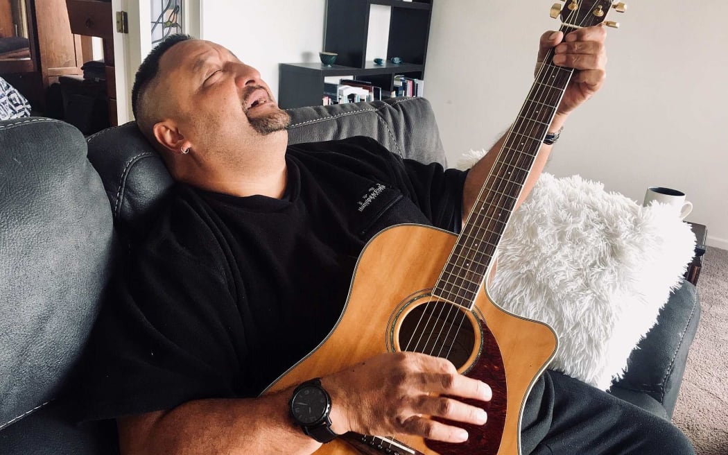 Man sitting o couch playing guitar