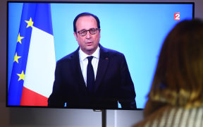 A person watches Francois Hollande's televised announcement that he will not seek a second term.