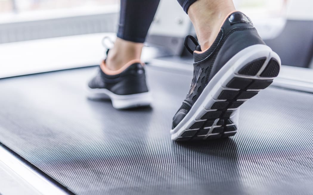 cropped shot of woman in jogging sneakers running on treadmill