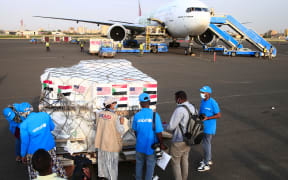 Aid workers check a shipment of vaccines against the coronavirus sent to Sudan by the Covax vaccine-sharing initiative, shortly after an Emirates plane landed at the airport in the capital Khartoum, on October 6, 2021.