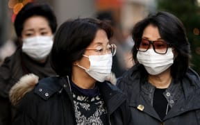 People wearing a mask walks past about the outbreak of coronavirus in Wuhan, China at Ginza shopping district in Tokyo, Japan, January 26, 2020.  (Photo by Hitoshi Yamada/NurPhoto)
