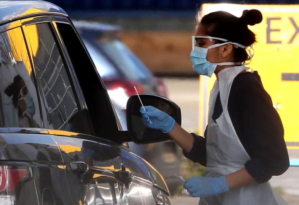A medical staff member wearing gloves, eye protection and a face mask, tests an NHS worker for the novel coronavirus COVID-19 at a drive-in facility set up in the car park of an IKEA store in Wembley, north-west London on April 4, 2020.