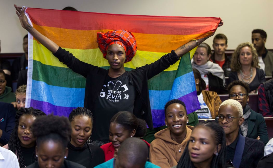 An activist holds up a rainbow flag to celebrate inside Botswana High Court in Gaborone on June 11, 2019. - Botswana's Court ruled on June 11 in favour of decriminalising homosexuality, handing down a landmark verdict greeted with joy by gay rights campaigners. (Photo by Tshekiso Tebalo / AFP)