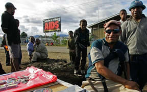 Residents sell their goods near a anti-Aids billboard in Mount Hagen, 18 August 2007.