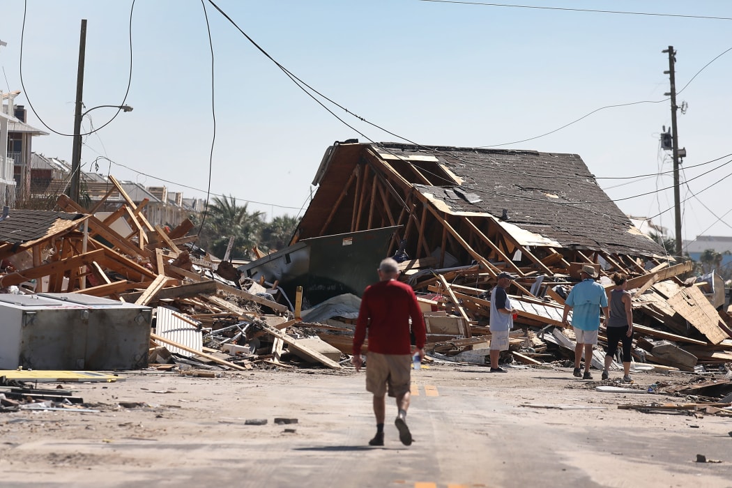 People walk along a street blocked by a building after Hurricane Michael passed through the area.