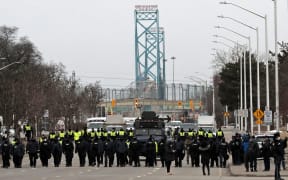 Police gather to clear protestors against Covid-19 vaccine mandates who blocked the entrance to the Ambassador Bridge in Windsor, Ontario, Canada, on 13 February 2022.