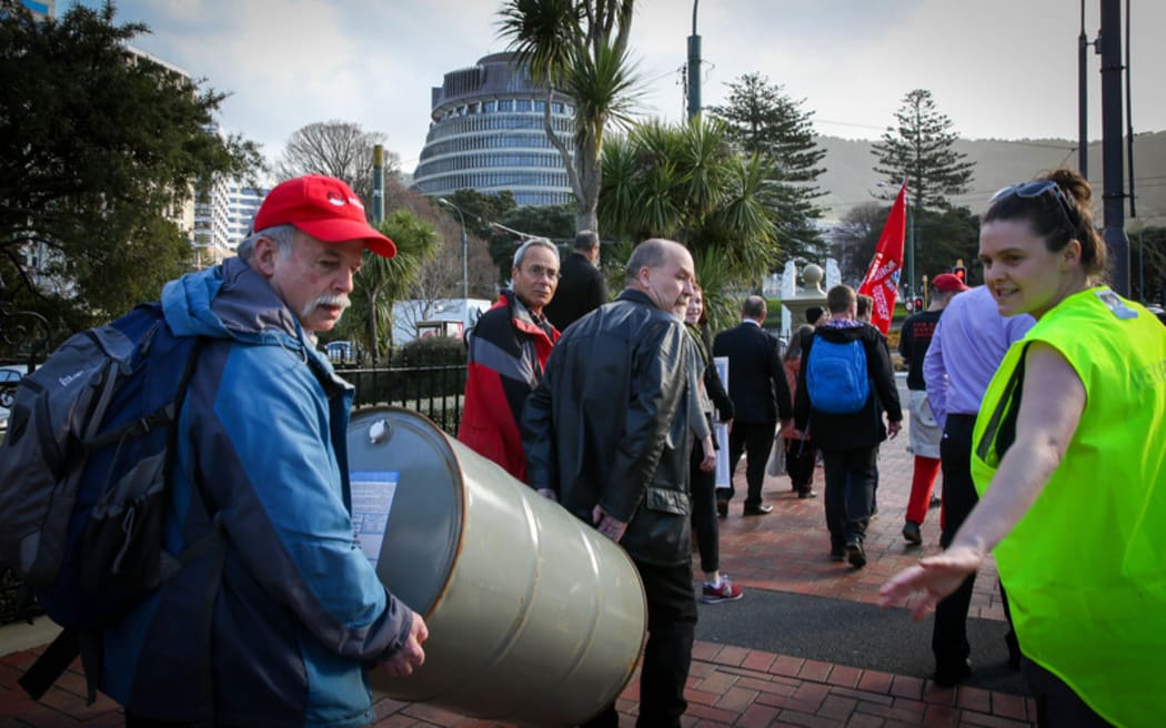 Protesters walk backwards from Parliament to the Wellington Train Station, highlighting the backwards move Kiwi Rail is making by replacing electric trains with diesel ones.